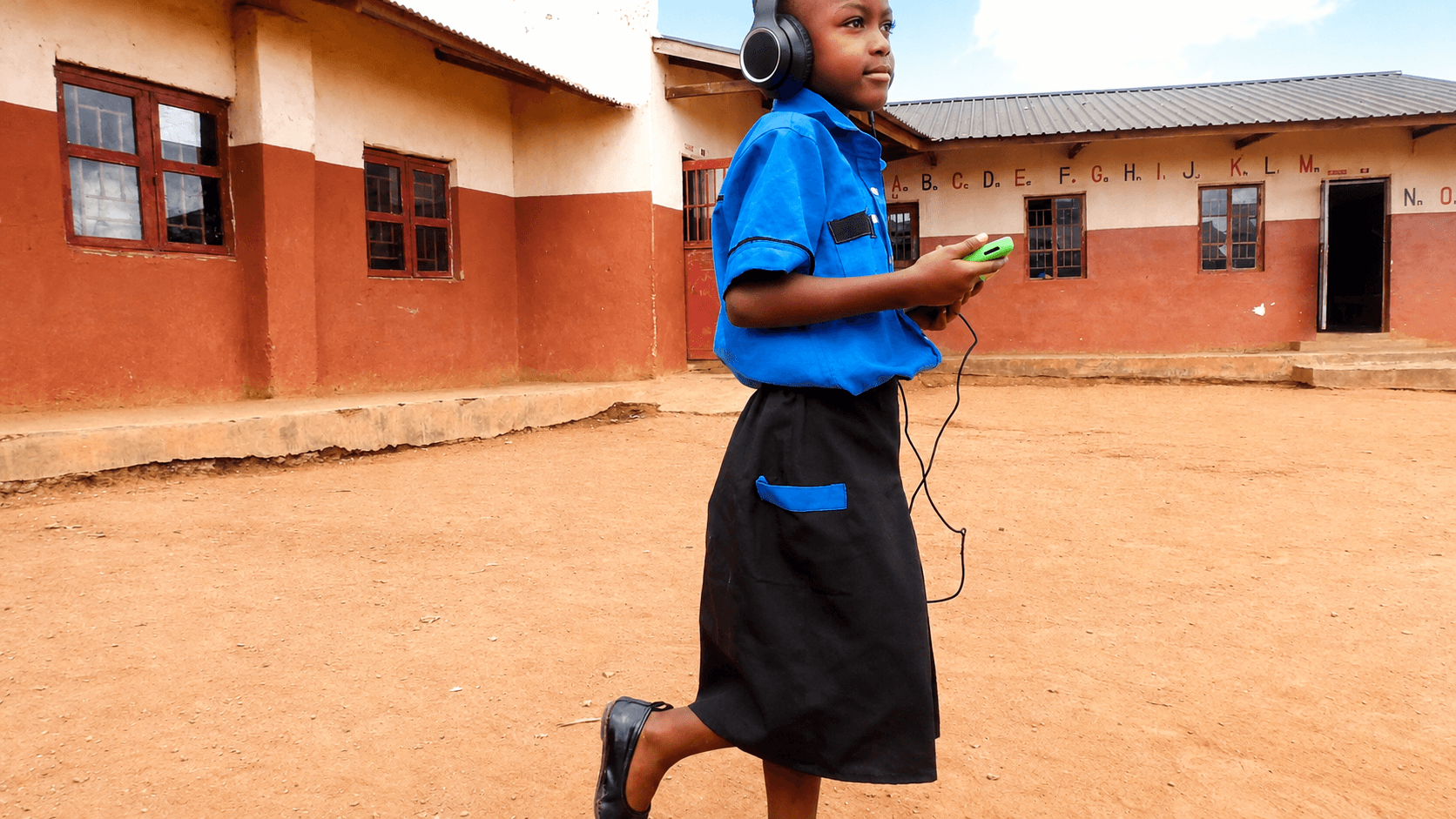 A student using a tablet and headphones outside an HFM school
